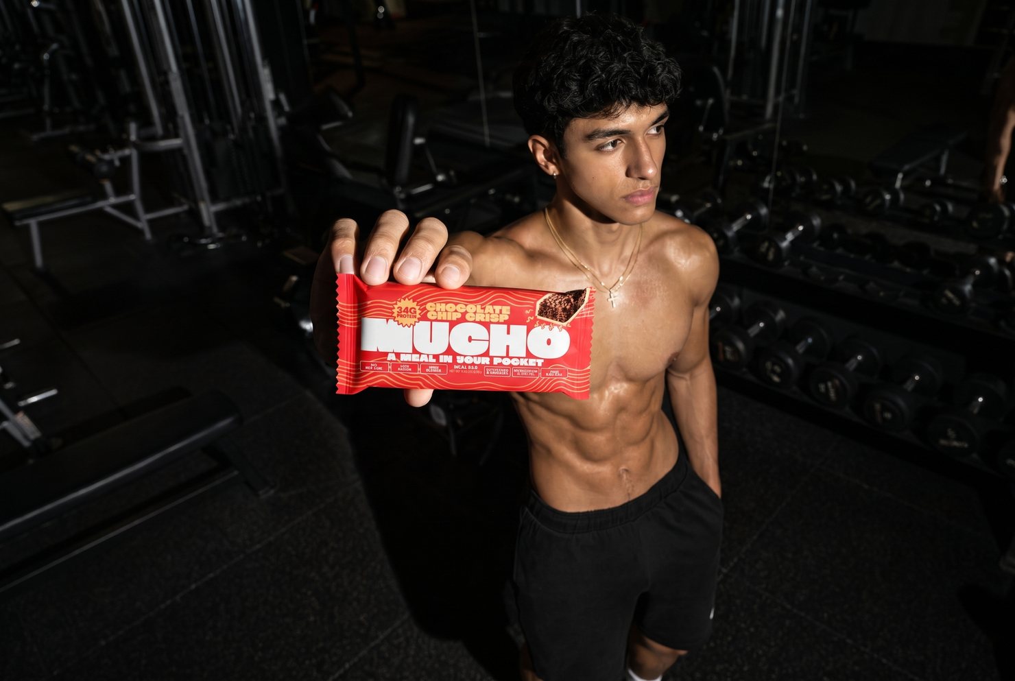 Man resting in a gym holding a Mucho protein bar