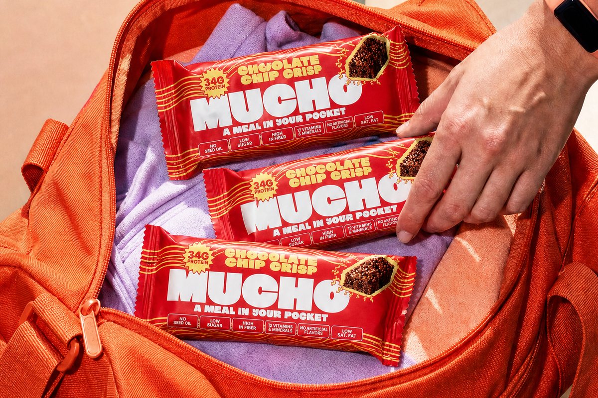 Three Mucho Chocolate Chip Crisp bars in an open orange gym bag on a stadium seat, a hand reaching in for one.