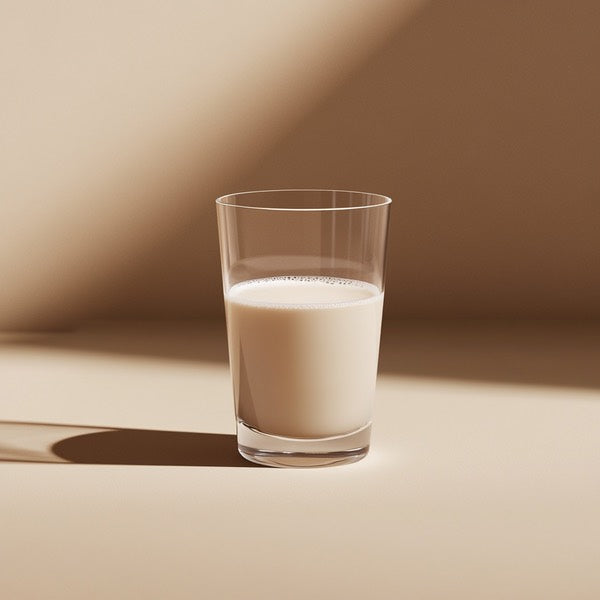 A glass of milk on a beige surface, with soft lighting.