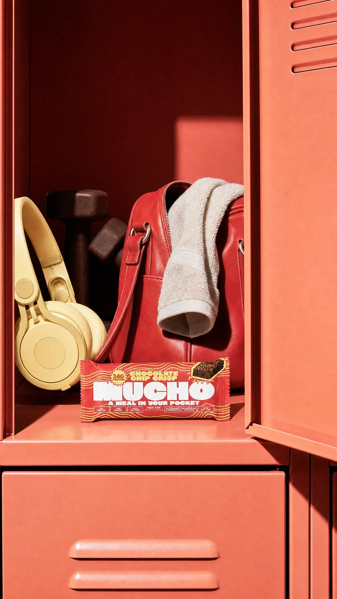 Mucho Chocolate Chip Crisp bar in a gym locker with headphones, dumbbells and a gym bag